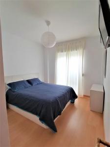 een witte slaapkamer met een blauw bed en een raam bij Apartamento Puntas del Moro in Villajoyosa