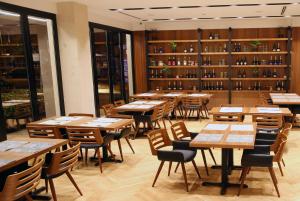 a restaurant with wooden tables and chairs and wine bottles at Hotel Theatro- City Center in Tirana