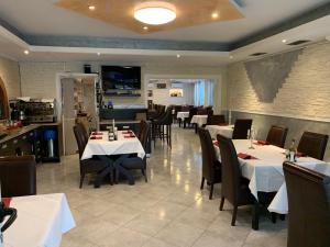 a dining room with white tables and chairs in a restaurant at Hotel Ristorante Sicilia in Tappenbeck