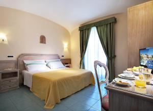 a bedroom with a bed and a table with a television at Hotel Royal Terme in Ischia