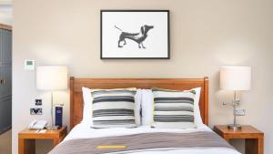 a bedroom with a bed with two lamps and a picture of a dog at voco Oxford Spires by IHG in Oxford