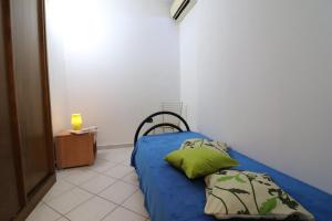 a bedroom with a blue bed with two green pillows at Casa vacanze Clio in Salento in Otranto