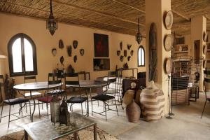 SfianiにあるFawakay Villasのテーブルと椅子、壁に花瓶が飾られた部屋
