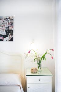 un jarrón de flores en una mesa junto a una cama en Casa Guadagno en Positano
