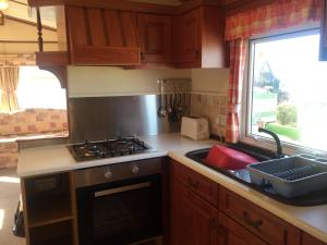 a kitchen with a stove and a sink and a window at Three bedroom Hartland Caravan in Bideford