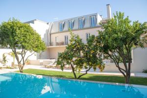 a villa with a pool and trees in front of it at Casa René - Charming apartments in Almada
