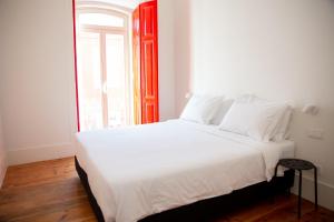 a white bed in a room with a window at Casa René - Charming apartments in Almada
