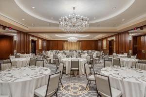 un salón de baile con mesas y sillas blancas y una lámpara de araña en Omni Houston Hotel en Houston