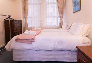 a bedroom with a white bed with a dresser and a window at Wellington CBD Apartment in Wellington