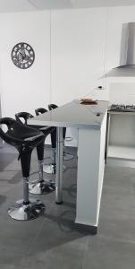 a white table with black chairs and a clock on a wall at La Kaz Kian in Sainte-Rose