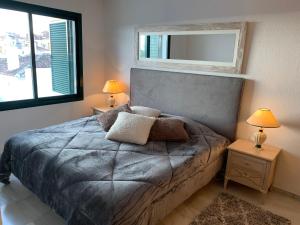 een slaapkamer met een bed met 2 lampen en een spiegel bij Pueblo Del Parque in Benalmádena
