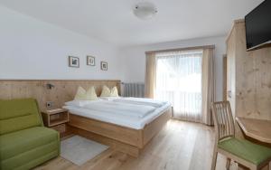 1 dormitorio con 1 cama grande y 1 silla verde en Gästehaus Luise, en Waidring