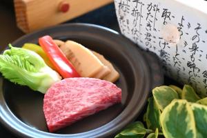 um prato de alimentos com carne e legumes sobre uma mesa em 原鶴の舞 em Asakura