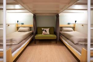 台南漫半拍 Lento Hostel 的客房设有两张双层床和一张绿色椅子。