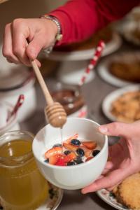 a person holding a bowl of fruit with a spoon at Hotel Meublè Garnì della Contea in Bormio +62 photos