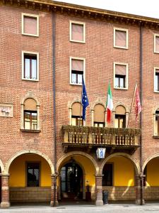a red brick building with a balcony and flags at Hotel Mignon in Padova