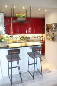 a kitchen with red cabinets and two bar stools at Varkiza Seaside Penthouse with Private Roof Deck in Vari