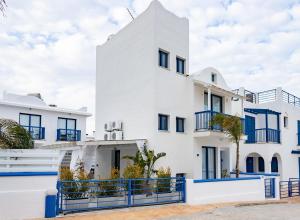 a white building with blue fences in front of it at Protaras Villa Nicol 21 in Paralimni