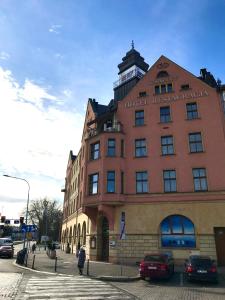 budynek na ulicy z samochodami zaparkowanymi przed nim w obiekcie Legnicki Browar Książęcy Hotel i Restauracja w mieście Legnica
