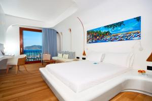 a white bedroom with a large bed and a balcony at Approdo Resort Thalasso Spa in Castellabate