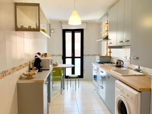 a kitchen with white cabinets and a counter with a table at La Vie en Rose Piso en el centro in Briviesca