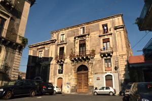un viejo edificio con coches aparcados delante de él en Casa Del Vecchio Bastione, en Catania