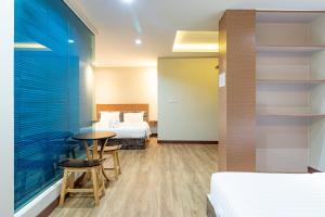 a hotel room with two beds and a table and chairs at Oun Residence in Hat Yai
