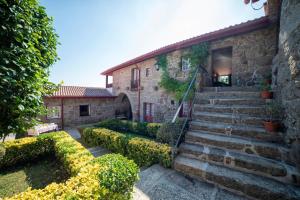 - un bâtiment en pierre avec des escaliers et des buissons en face dans l'établissement Quinta De Cima De Eiriz, à Guimarães