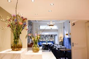 アムステルダムにあるHotel Asterisk, a family run hotelの花瓶とテーブルのあるダイニングルーム