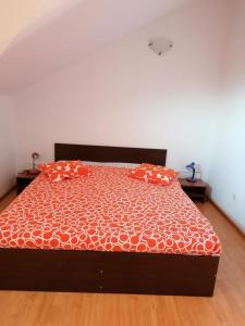 Una cama con dos almohadas naranjas encima. en Villa Edera Residence - Gazda Profesionista, en Bucarest