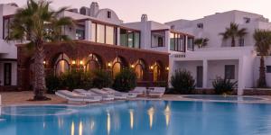 a villa with a swimming pool in front of a building at Maison Des Lys - Luxury Suites in Akrotiri