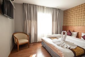 CBD Hotel Suratthani في سوراثاني: غرفة نوم بسرير وكرسي ونافذة