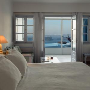a bedroom with a bed and a glass of wine at Maison Des Lys - Luxury Suites in Akrotiri
