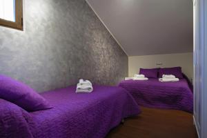 two beds in a room with purple sheets at LOS ALISOS in Coca