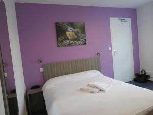 サン・タヴェルタンにあるHotel le Faisanの紫の壁の白いベッドが備わるベッドルーム1室
