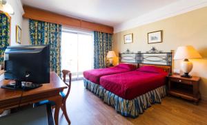 a bedroom with a red bed and a desk with a television at Topaz Hotel in St Paul's Bay