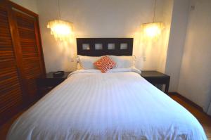 sypialnia z dużym białym łóżkiem z dwoma stołami w obiekcie Villas Sur Mer w Negril