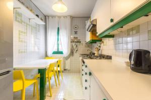 トレヴィーゾにあるDadahome elegante appartamento vicino al centroのキッチン(白いカウンター、黄色い椅子付)
