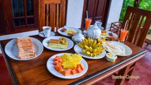 einem Holztisch mit Teller mit Lebensmitteln darauf in der Unterkunft Sunrise Cottage in Sigiriya