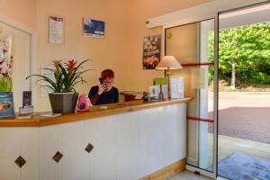 a woman sitting at a counter talking on a cell phone at Logis Hôtel Val de Vienne in Le Vigeant