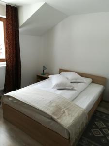 a bed with white sheets and pillows in a bedroom at De la mare la munte in Vatra Dornei