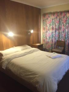 um quarto de hotel com uma cama branca e uma cadeira em Meekatharra Hotel em Meekatharra