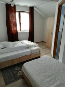 two beds in a small room with a window at De la mare la munte in Vatra Dornei