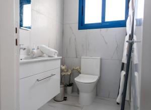 a white bathroom with a toilet and a window at Protaras Villa Nicol 21 in Paralimni +37 photos