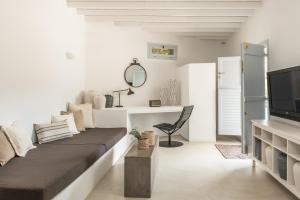 a white living room with a couch and a tv at Verina Terra in Platis Gialos