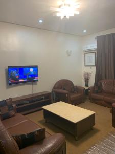 uma sala de estar com mobiliário de couro e uma televisão de ecrã plano em Greens Manor VI em Lagos