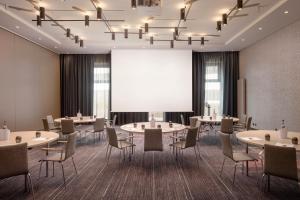 een conferentiezaal met tafels en stoelen en een projectiescherm bij Holiday Inn Hamburg - City Nord, an IHG Hotel in Hamburg