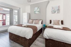 two beds in a room with white walls and windows at Superb Spacious House For Contractors & Families & Private Parking By Liverpool Short Stay in Liverpool