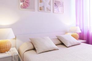 a white bedroom with a bed and two lamps at Casa Gelso in Marciana