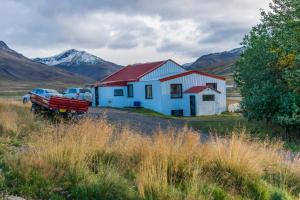 ein Haus auf einem Feld mit Bergen im Hintergrund in der Unterkunft Ravencliff Lodge in Búðardalur